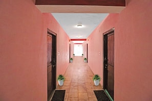 A corridor with pink walls, tiled floor, and doors on both sides. - Hotel O by OYO Hema Holiday Home (Manali)