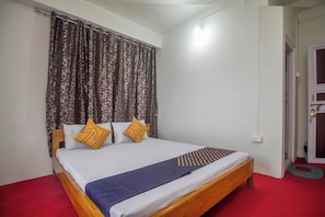 Uma cama de solteiro com estrutura de madeira, roupa de cama branca e duas almofadas decorativas.