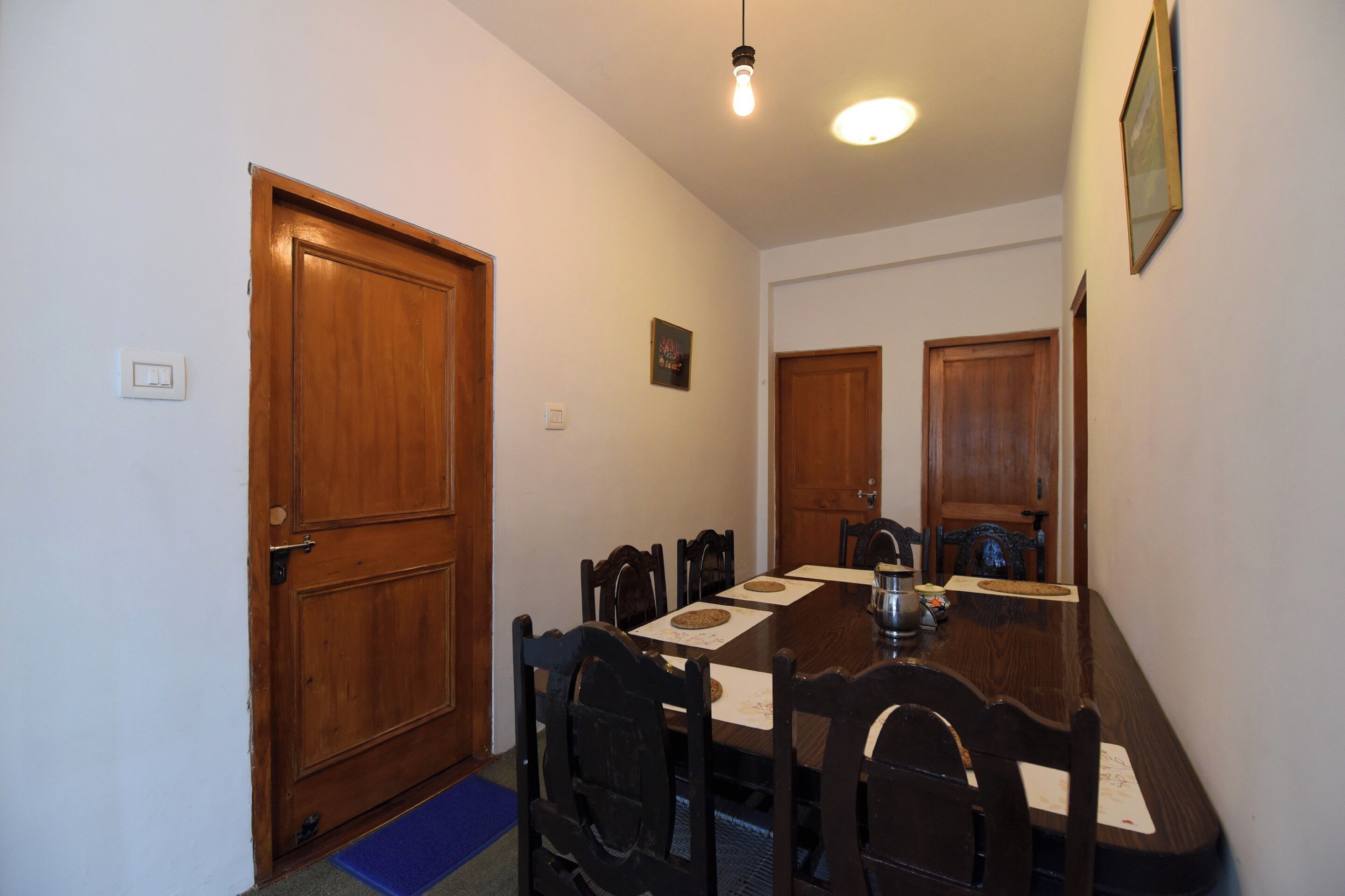 Un comedor con una mesa de madera, sillas, un tapete azul y una lámpara.