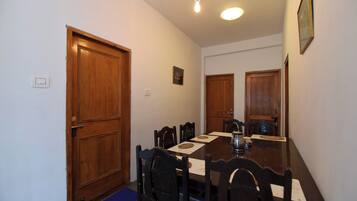 Un comedor con una mesa de madera, sillas, un tapete azul y una lámpara.