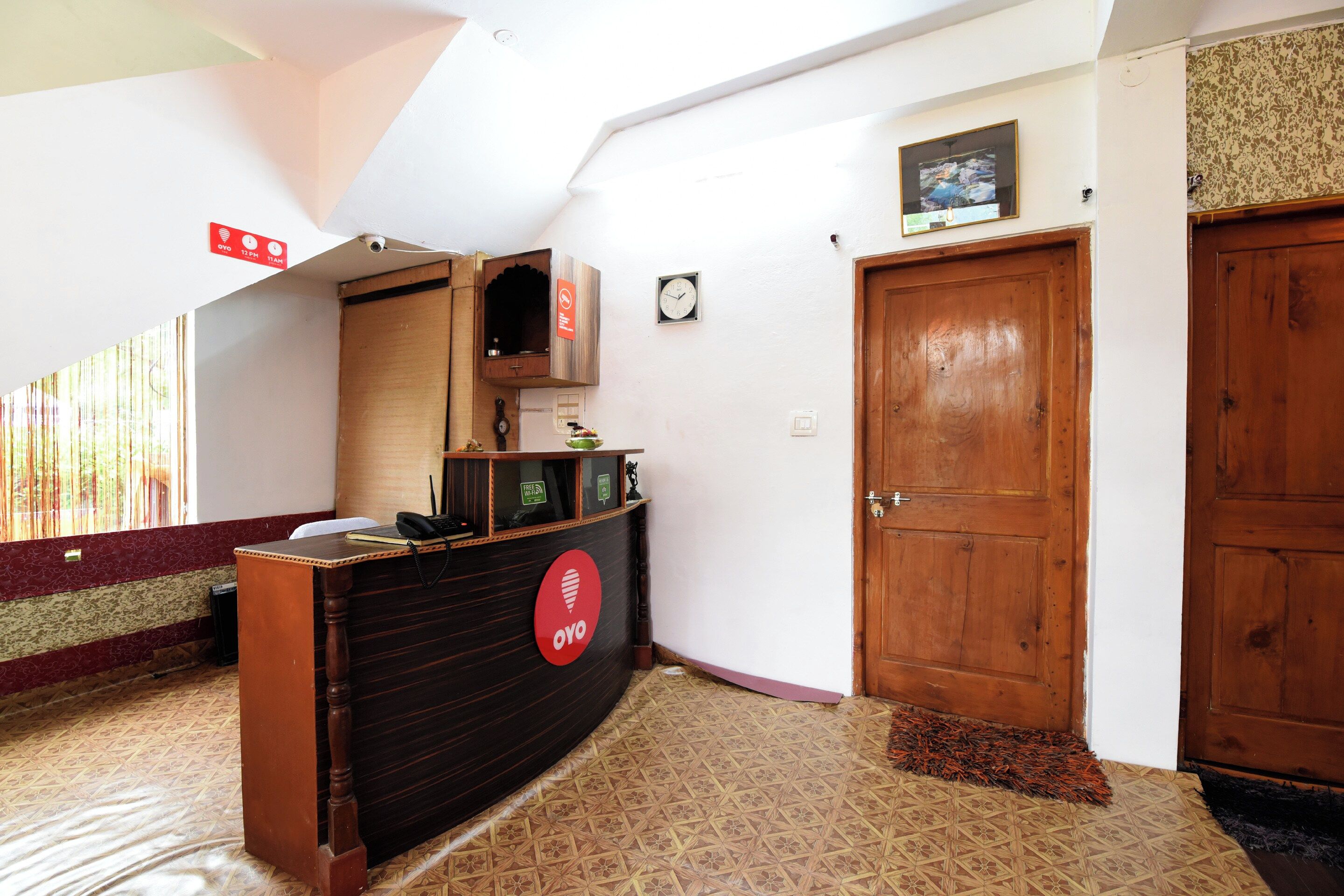 Bancada de recepção com relógio, porta e piso estampado.