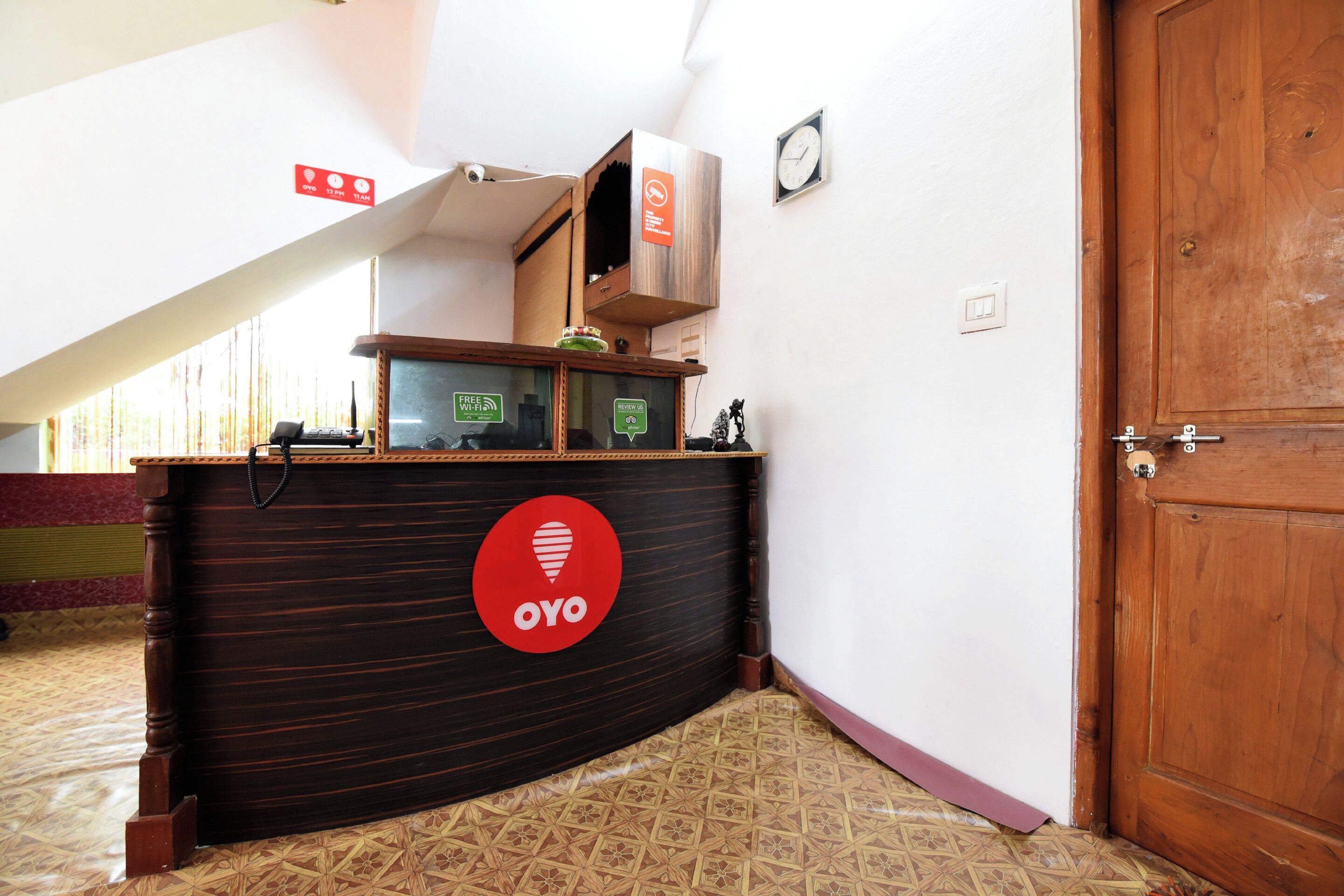 Un mostrador de recepción con detalles de madera, un reloj en la pared y una puerta a la derecha.