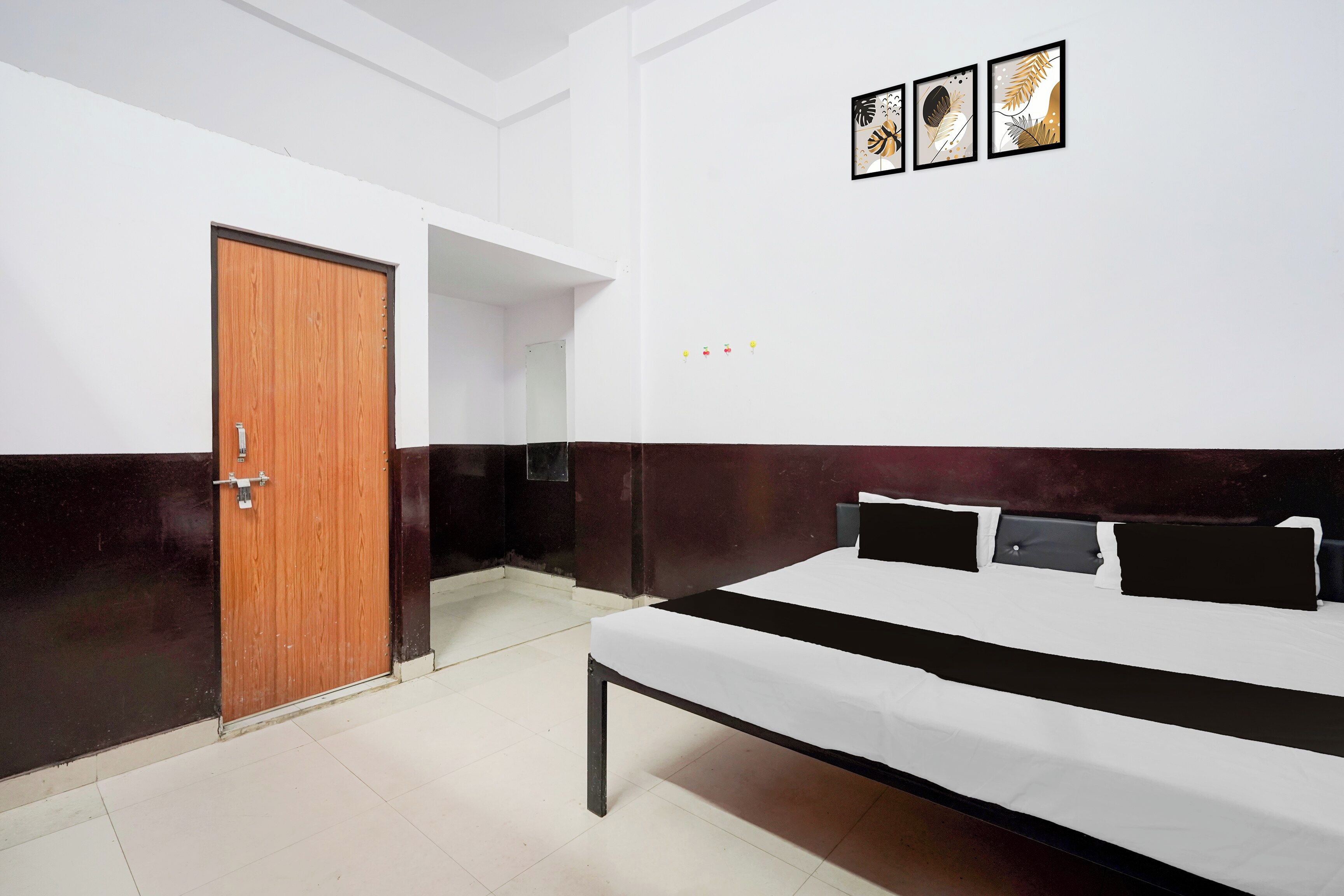 Una camera da letto con un letto, una porta in legno e tre quadri appesi al muro.