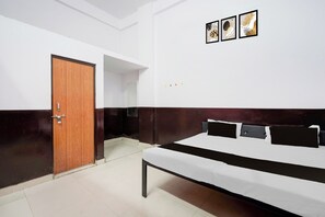Un dormitorio con una cama, una puerta de madera y tres cuadros en la pared.