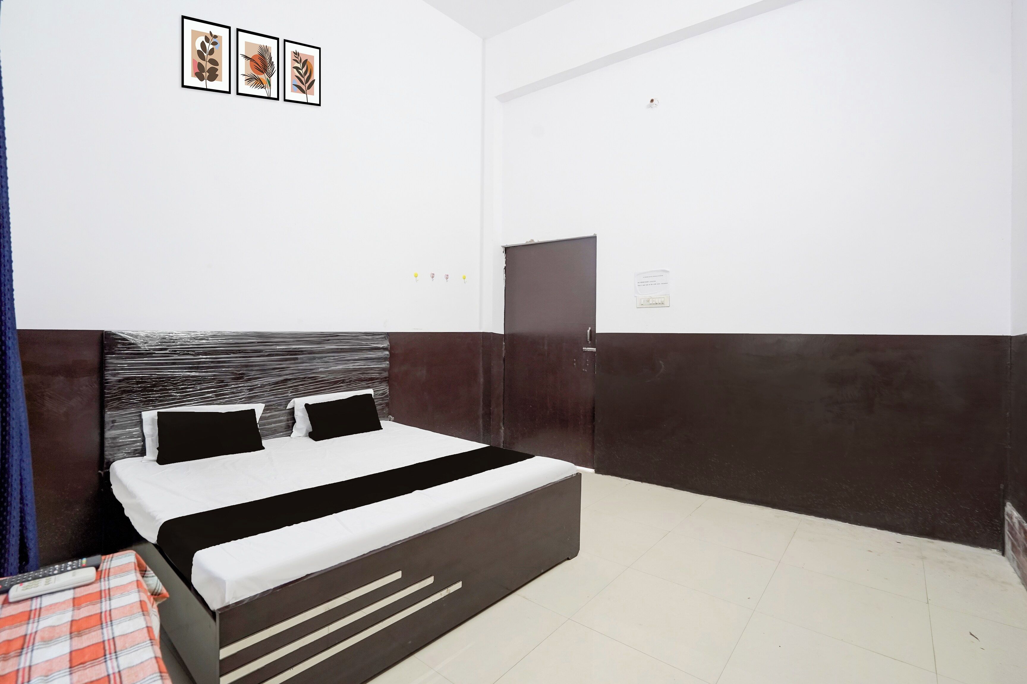 Habitación de hotel con cama, mesita de noche, armario y un interruptor de luz en la pared.