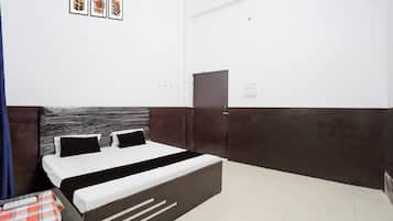 Habitación de hotel con cama, mesita de noche, armario y un interruptor de luz en la pared.