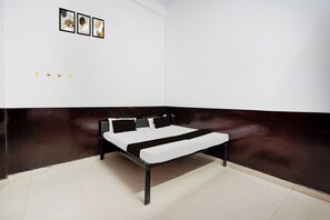 A room with a bed, a dark accent wall, and three framed pictures on the wall.