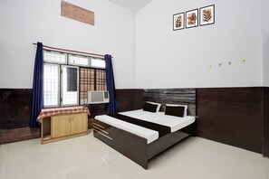 A bedroom with a bed, a wardrobe, a window with curtains, and wall art. - HOTEL O SP GRAND (Mahmudabad)