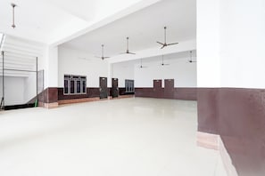 A spacious room with a high ceiling, multiple ceiling fans, and a large open area with a tiled floor. - HOTEL O SP GRAND (Mahmudabad)