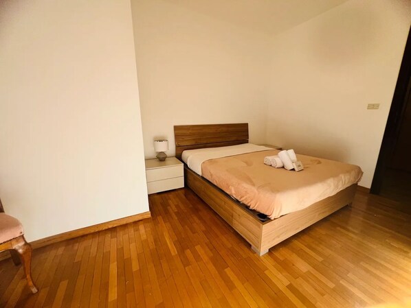 A single bed with a wooden headboard, a bedside table with a lamp, and a chair. - New Listing (Sanremo)