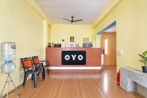 A reception area with a reception desk labeled 'OYO,' a water dispenser, chairs, and a ceiling fan.