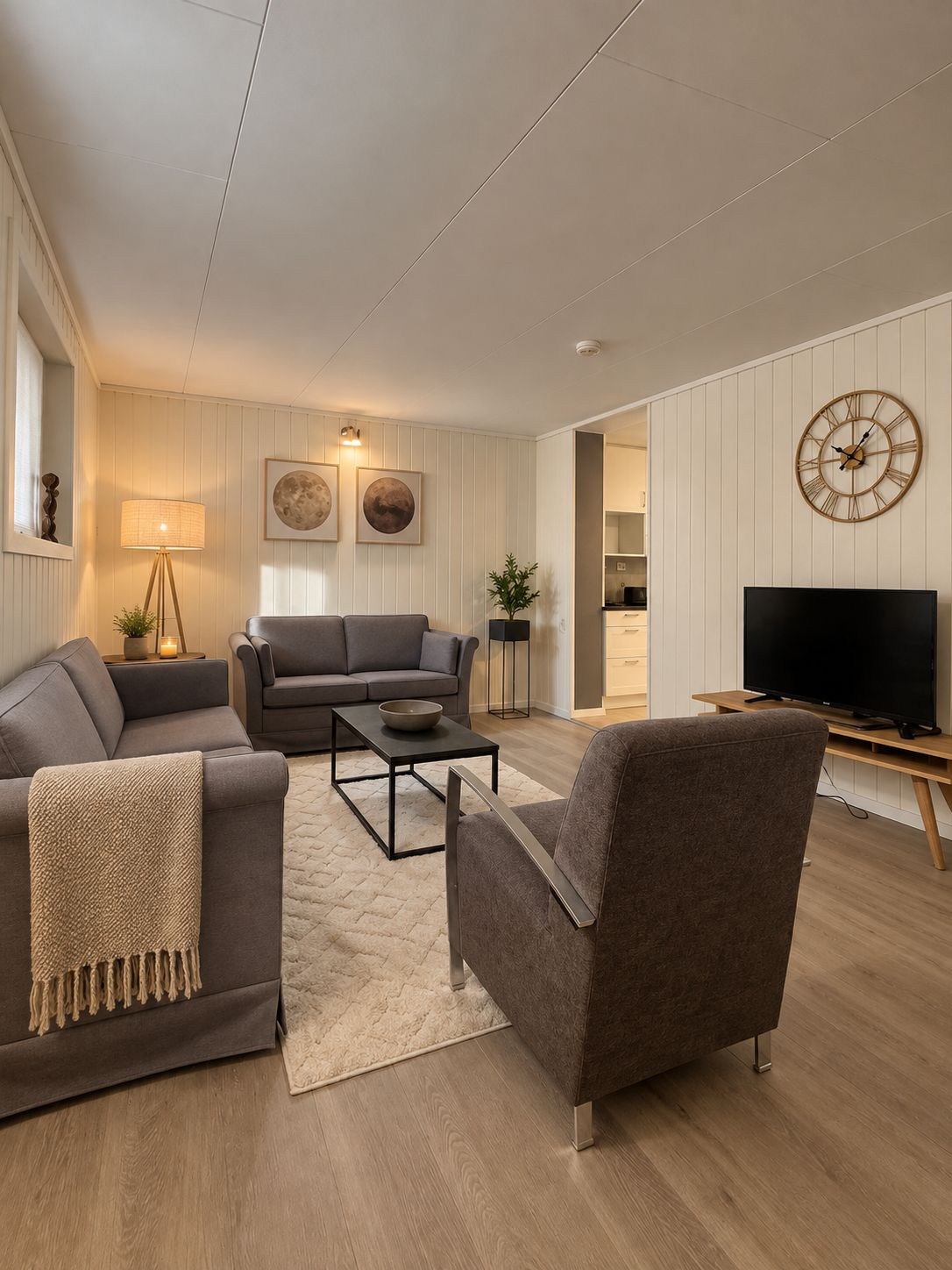 A modern living room with a sofa, armchair, coffee table, and a television.