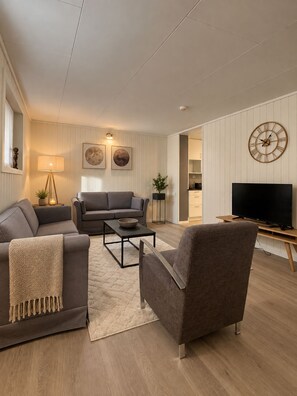 A modern living room with a sofa, armchair, coffee table, and a television. - Cozy Tromsø Home with Fjord View & Northern Lights (Tromsø)