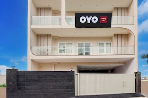 Un hotel de varios pisos con un llamativo letrero 'OYO Galaxy Inn', una entrada con portón y un balcón en el piso superior.