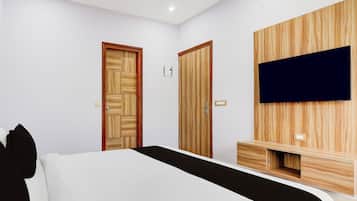 Un dormitorio con una cama, dos armarios de madera, un televisor montado en la pared y una mesita de noche.