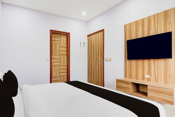 Un dormitorio con una cama, dos armarios de madera, un televisor montado en la pared y una mesita de noche.