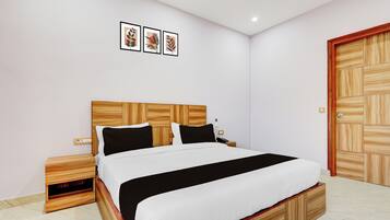 Un dormitorio con cabecera de madera, cama con ropa de cama blanco y negro, mesita de noche, teléfono y armario de madera.