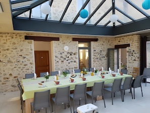 A dining area with a long table, chairs, and a ceiling with a skylight. - Holiday Home 'L'aile Ouest De La Ferme' with Wi-Fi and Air Conditioning (Senlisse)