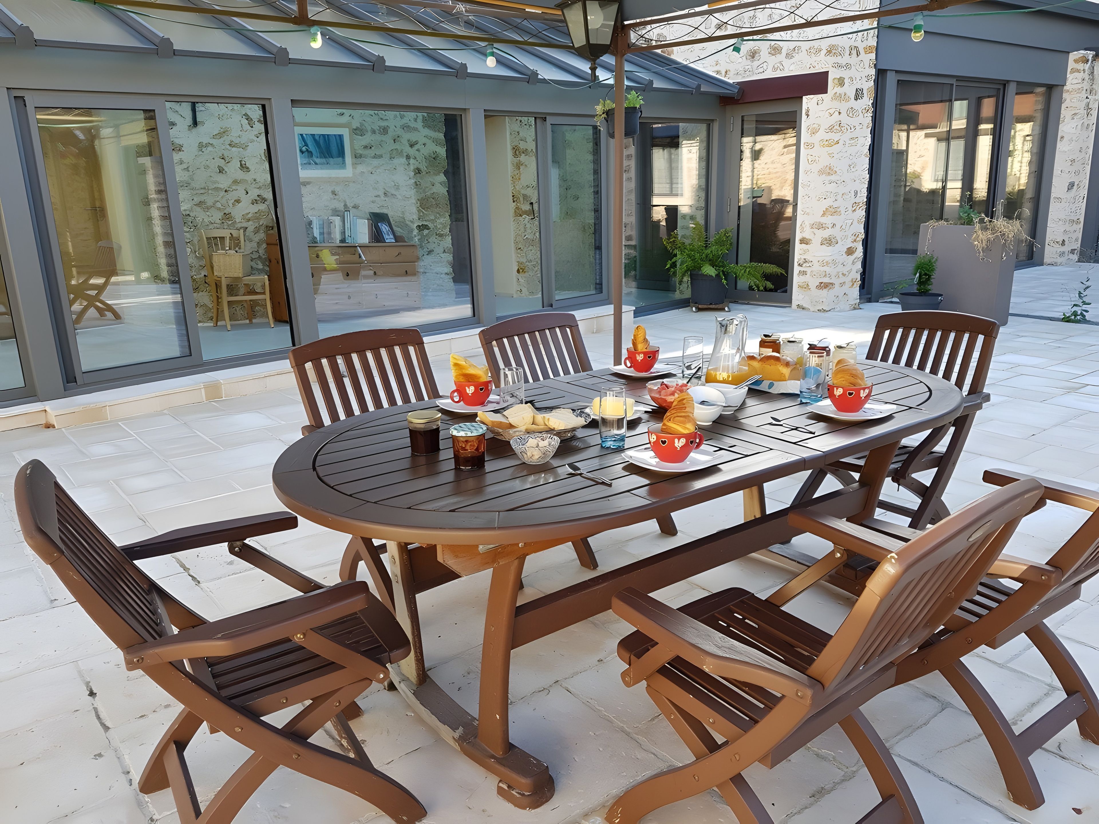 Een terras met een ronde tafel, stoelen en diverse gerechten en drankjes.
