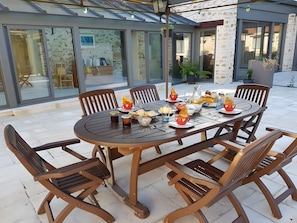 An outdoor dining area with a round table, chairs, and a variety of food and drink items. - Holiday Home 'L'aile Ouest De La Ferme' with Wi-Fi and Air Conditioning (Senlisse)