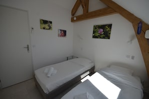 A small, single-bed room with a wooden ceiling, a white door, and two framed pictures on the wall. - Holiday home 'Grande Suite' with Wi-Fi and air conditioning (Senlisse)
