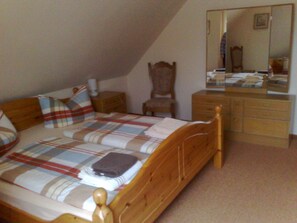 A bedroom with a wooden bed, a nightstand, a dresser, and a mirror. - Apartment 'Kuehl-FeWo' with Shared Terrace, Private Garden and Wi-Fi (Sehestedt)
