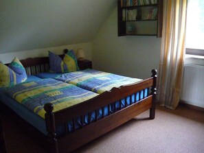 Een bed met een houten frame en een deken met blauwe en gele delen.