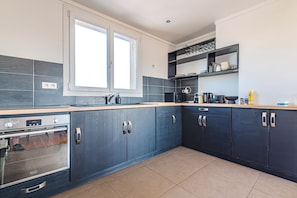 A modern kitchen with dark cabinetry, a built-in oven, and a window above the sink. - New Listing (Reims)