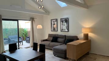 Een moderne woonkamer met een bank, een eettafel, stoelen, een lamp en ingelijste foto's aan de muur.
