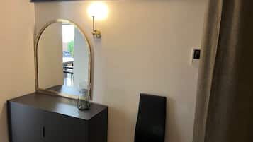 Een badkamer met een zwart wastafelmeubel, een grote spiegel, een wandlamp en een douchegordijn.