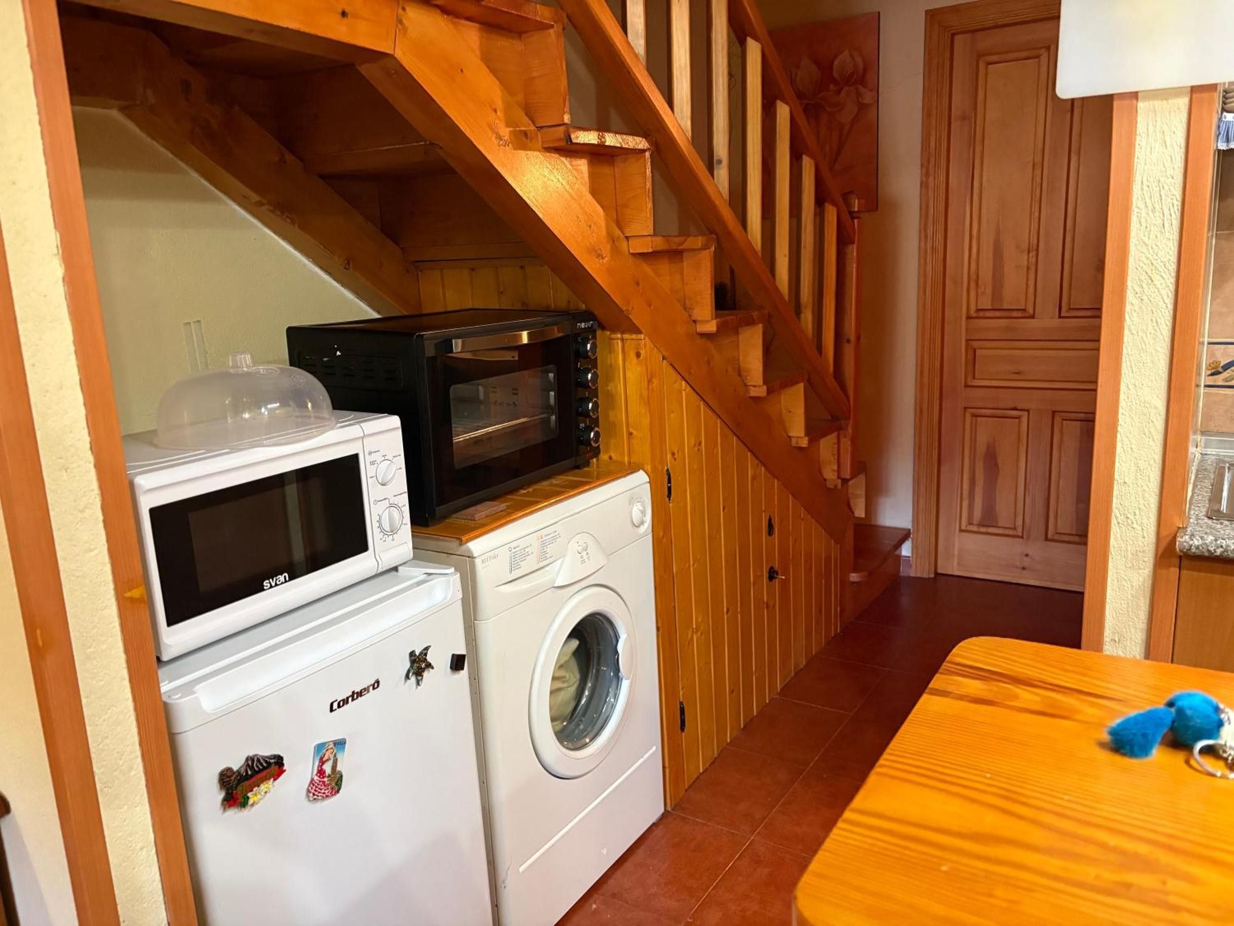 Een kleine keuken met een magnetron, broodroosteroven en een wasmachine.
