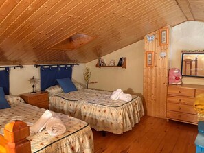 Ein gemütliches Schlafzimmer im Dachgeschoss mit zwei Betten, einem Schminktisch und einer Kommode.