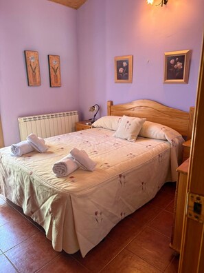 Un dormitorio con cama, mesita de noche, lámpara y radiador.