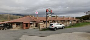 Un edificio con techo de tejas rojas, un coche aparcado y un cartel que indica restaurante y bar.