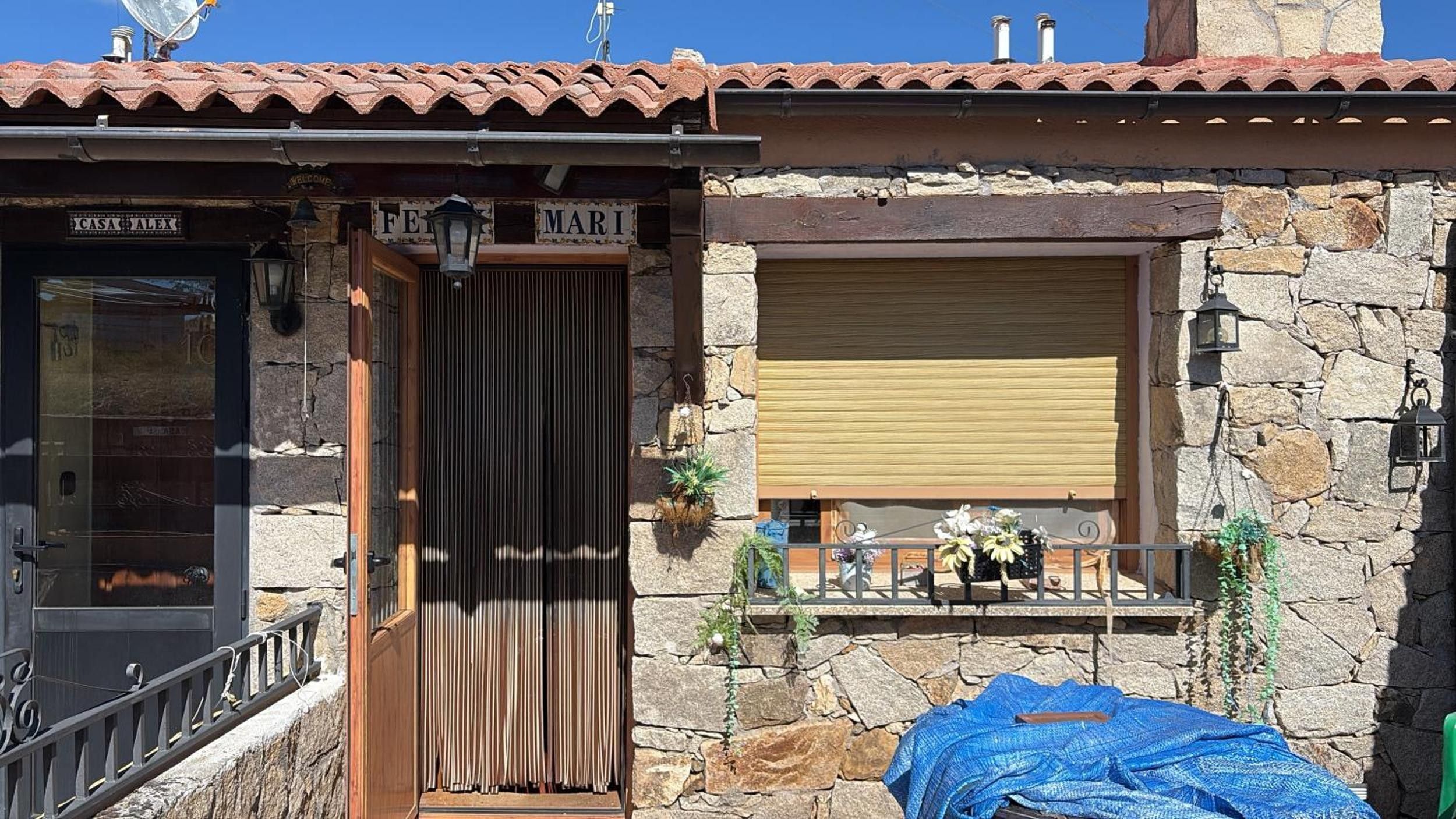 Edifici de pedra amb una porta de fusta, una finestra amb persiana i un rètol que diu 'MARI'.