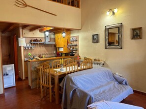 Una cocina acogedora con armarios de madera, una mesa de comedor y sillas. Incluye una pequeña isla con un lavaplatos y un refrigerador.