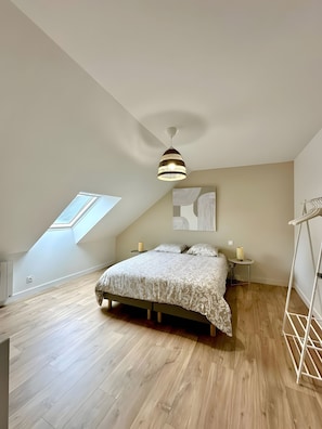 A bedroom with a sloped ceiling, a bed with a patterned bedspread, a hanging light fixture, a small bedside table with a lamp, and a skylight. - Holiday Home 'Grand Gîte De Standing 14 Pers' with Private Terrace, Private Garden and Wi-Fi (Alençon)
