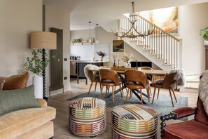 A modern interior with a dining area, staircase, and a view of the kitchen.