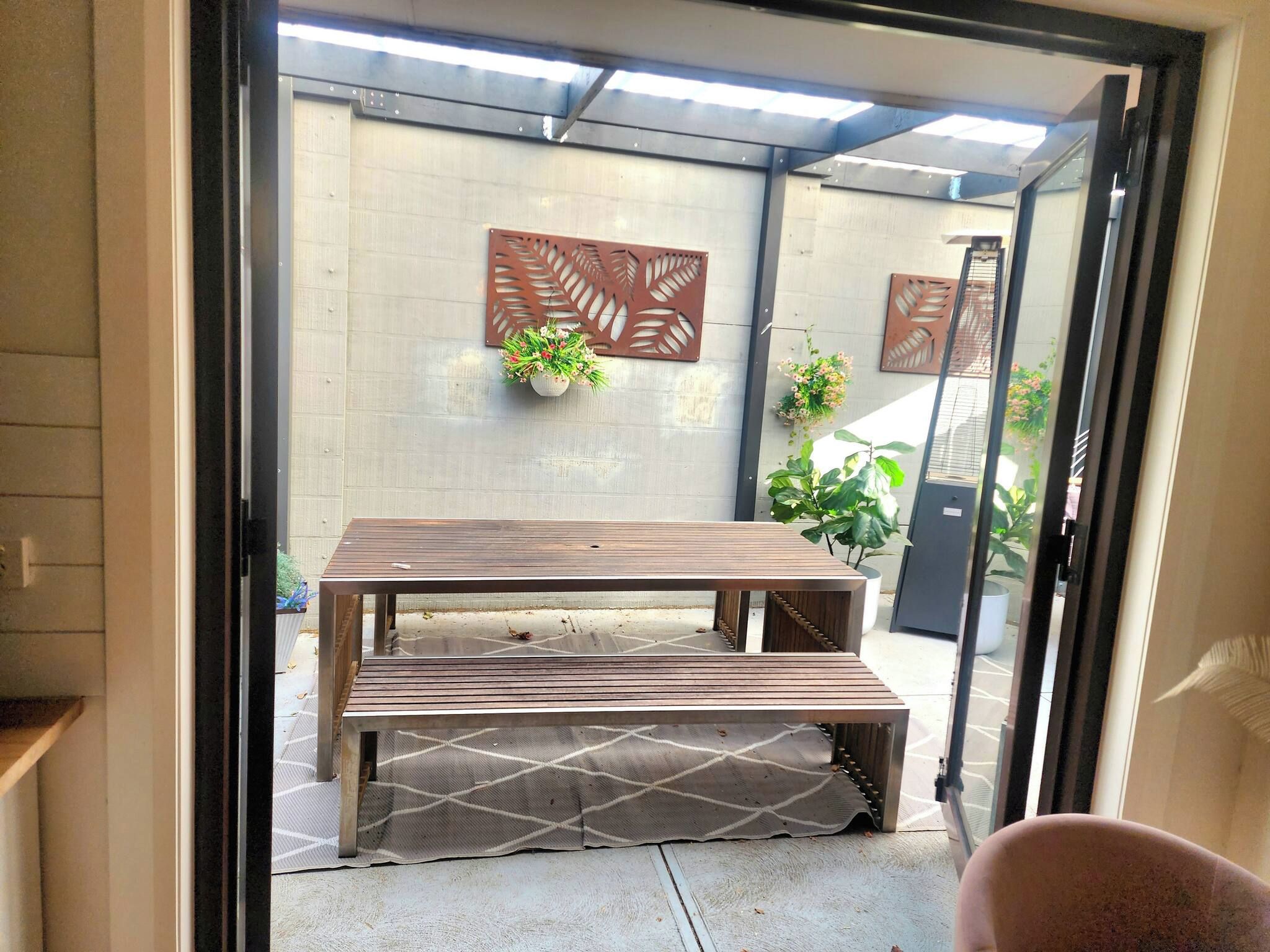Mesa de madera con bancos en un espacio exterior cubierto con vistas al jardín.