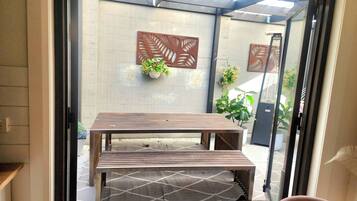 Mesa de madera con bancos en un espacio exterior cubierto con vistas al jardín.