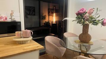 Una cocina moderna con microondas, cafetera y un florero con flores sobre una mesa de vidrio.