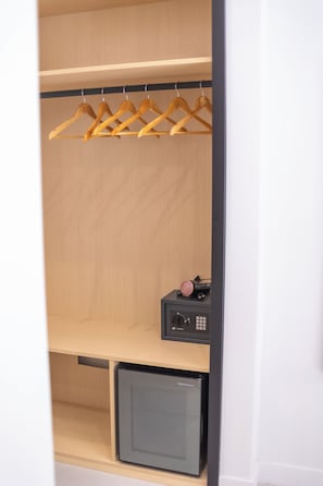 A wardrobe with wooden hangers, a black hairdryer, and a small black appliance on the bottom shelf. - The Ease (Naples)
