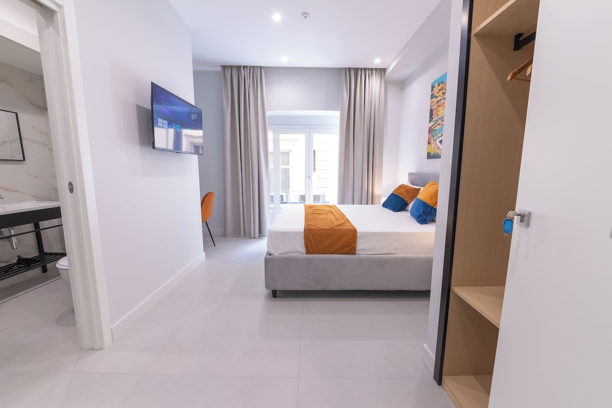 Een moderne hotelkamer met een bed, een televisie, een badkamer en uitzicht.