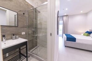 Een moderne badkamer met een douchecabine van glas, een wastafelmeubel en een spiegel.