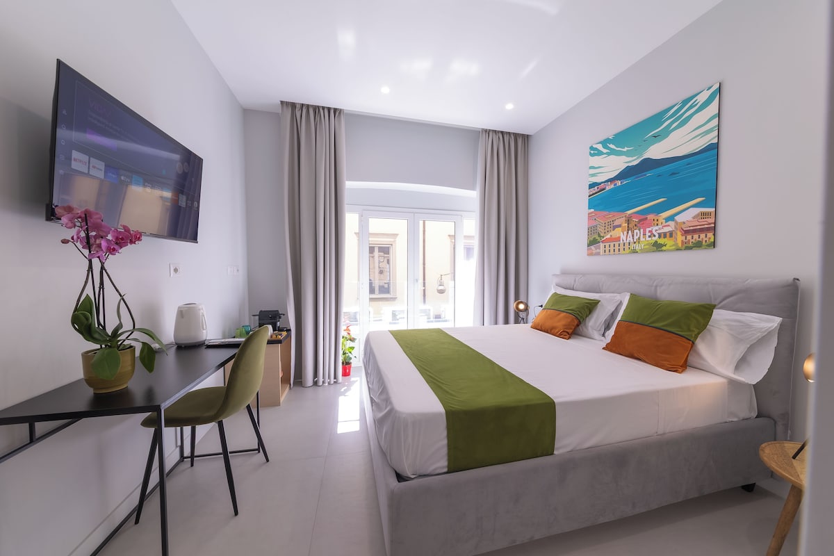 Een hotelkamer met een bed, een bureau, een stoel, een televisie en een schilderij.