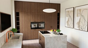 Cozinha moderna com forno embutido, bancada de mármore e luminária pendente.
