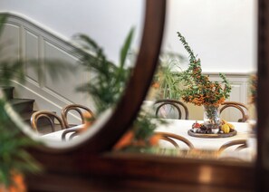 Une table à manger ornée d’un vase de fleurs et d’une composition centrale composée de citrouilles et de pommes de pin.