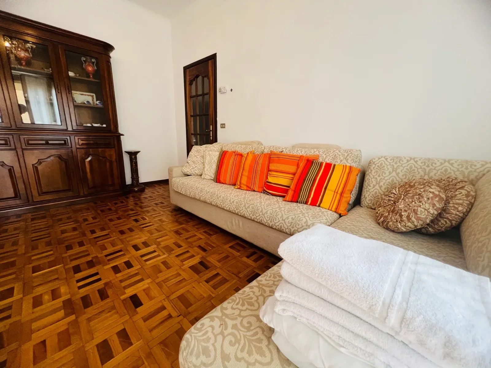 A living room with a patterned sofa, a wooden cabinet, and a patterned rug.