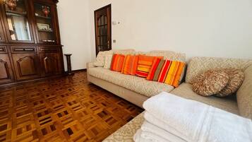A living room with a patterned sofa, a wooden cabinet, and a patterned rug.
