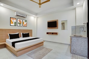 A modern bedroom with a bed, bedside tables, a ceiling fan, wall-mounted TV, and a bathroom with a sink and mirror. - Hotel O D'Empire (Gurugram)